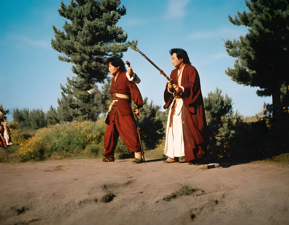 Two people in red robes practicing martial arts with swords outdoors.