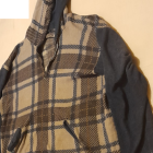 Fashionable oversized checker-patterned jacket with unique patches and gold necklace.