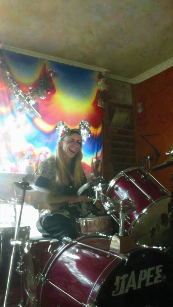 Smiling person with cat ears playing drums in cosmic setting