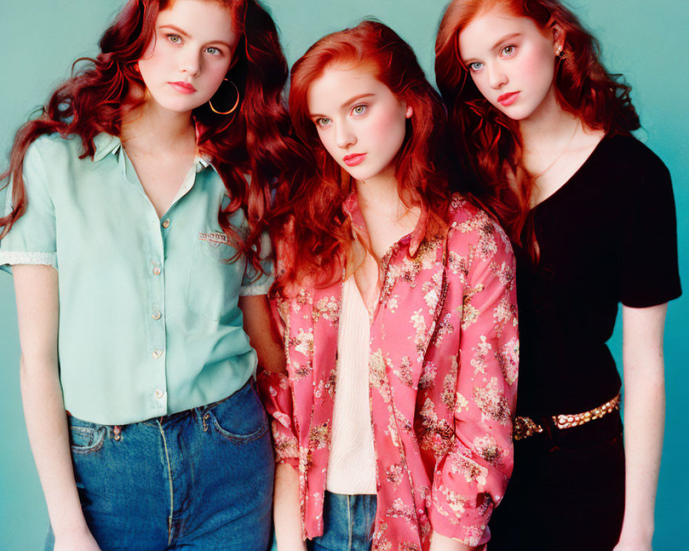 Three Red-Haired Women in Stylish Outfits on Teal Background