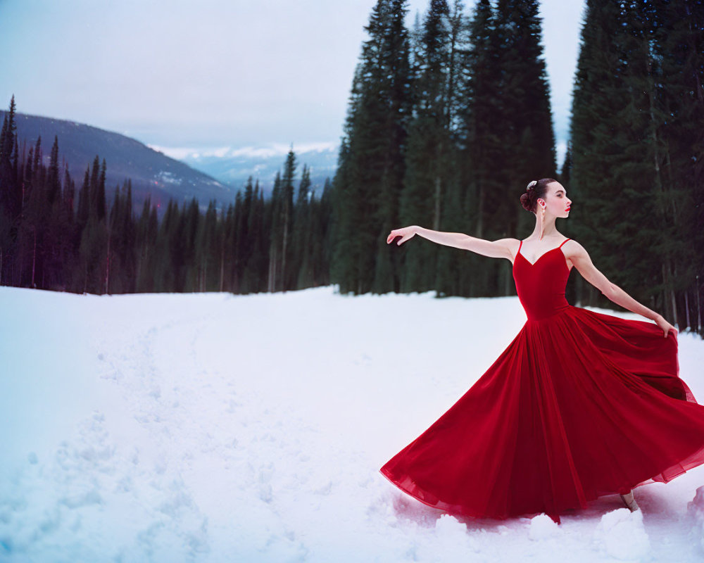 Woman in red dress posing in snowy forest landscape with pine trees and mountain.
