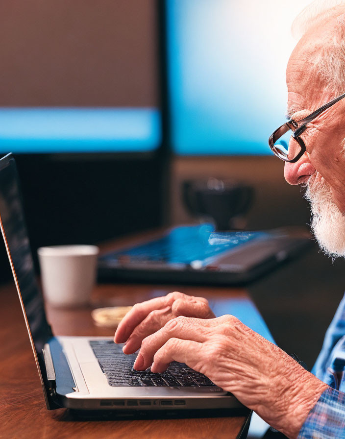 Elderly Person Typing on Laptop with Glasses in Room