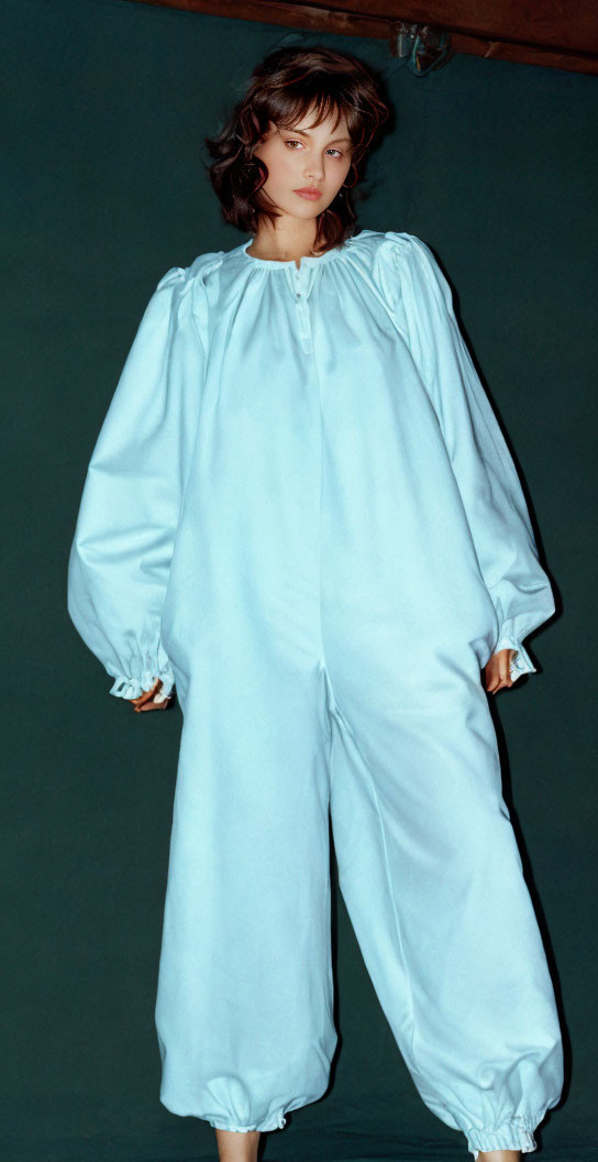 Person in Voluminous Light Blue Garment on Dark Background