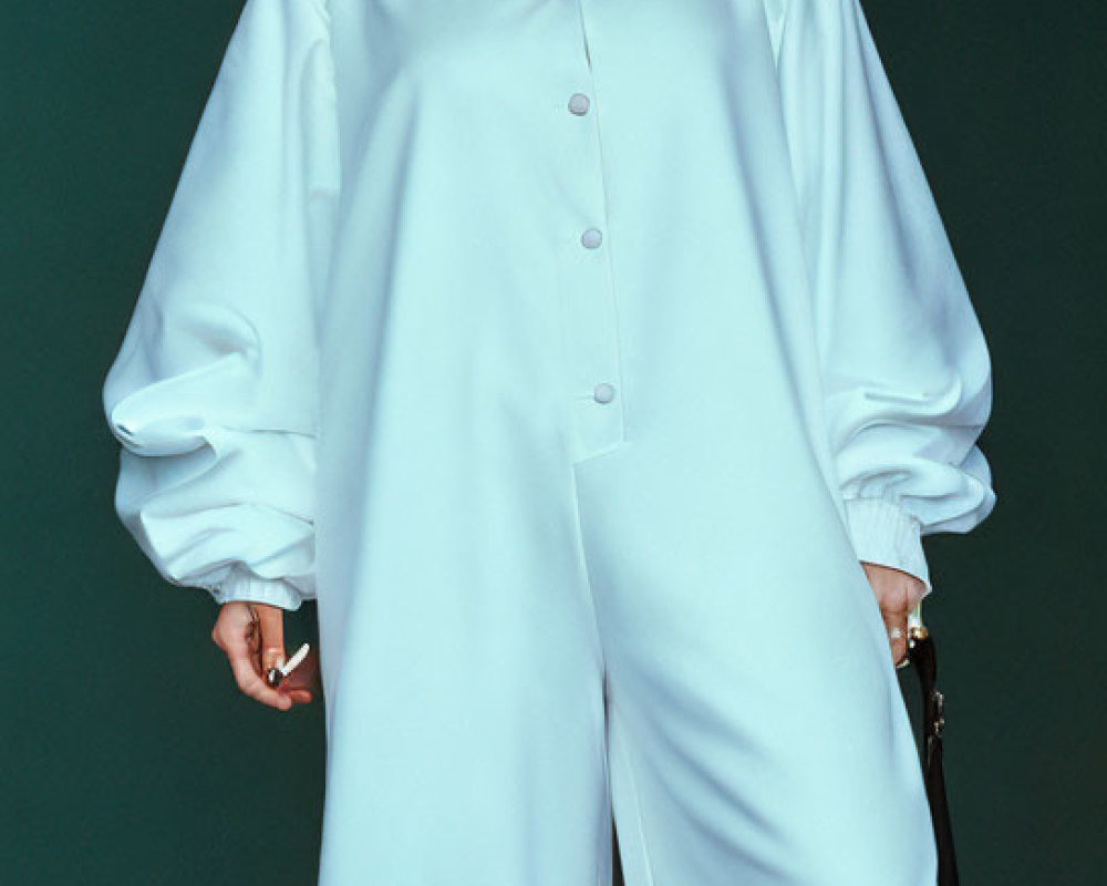 Woman in Blue Satin Jumpsuit with Puffed Sleeves and Clutch Against Teal Background