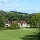 Tranquil pastoral landscape with green hills, grazing sheep, and red-roofed farmhouses