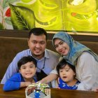 Family of Four with Owl Plushies on Wooden Bench in Lush Garden