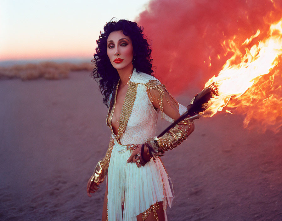 Dark Curly-Haired Woman Holding Flaming Torch in White and Gold Outfit