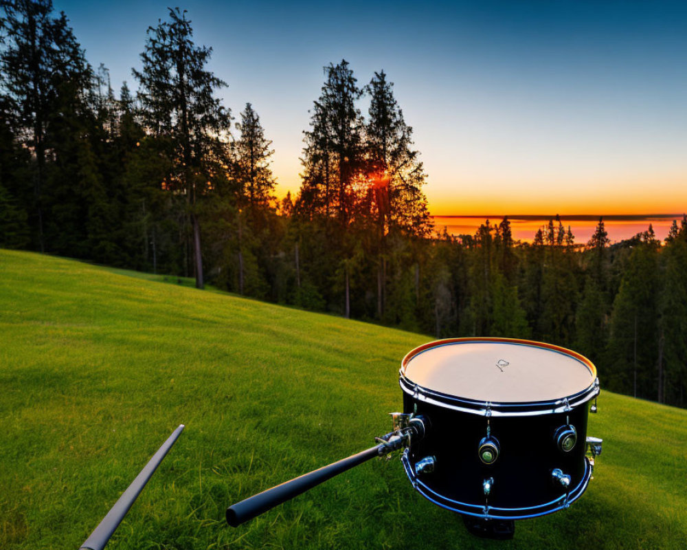 Snare Drum and Drumsticks on Grassy Hillside at Sunset