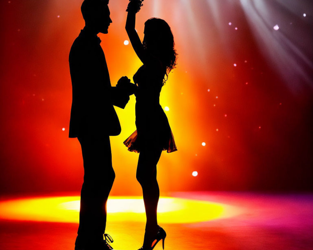 Silhouetted couple dancing on stage with colorful spotlight and haze
