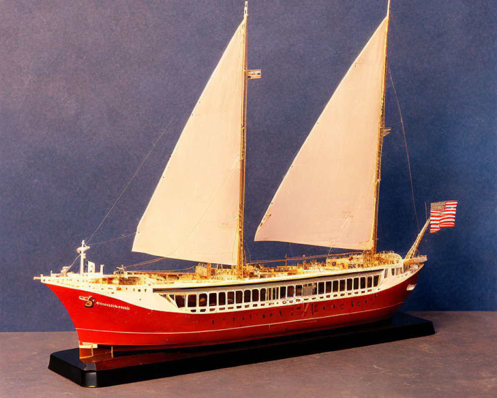 Detailed Classic Sailboat Model with Red Hull and American Flag on Stand