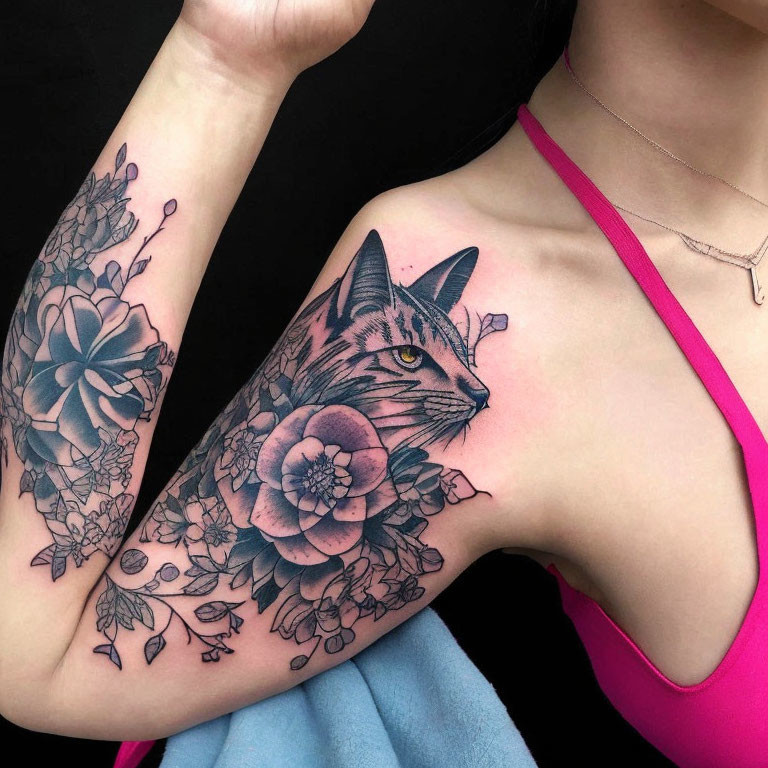 Cat Face Tattoo with Flowers and Leaves on Arm Against Black Background