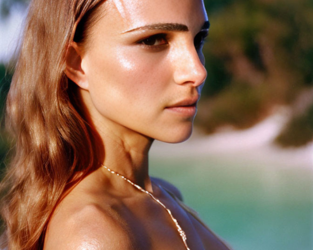 Woman with sun-kissed skin in white top and necklace gazes serenely.