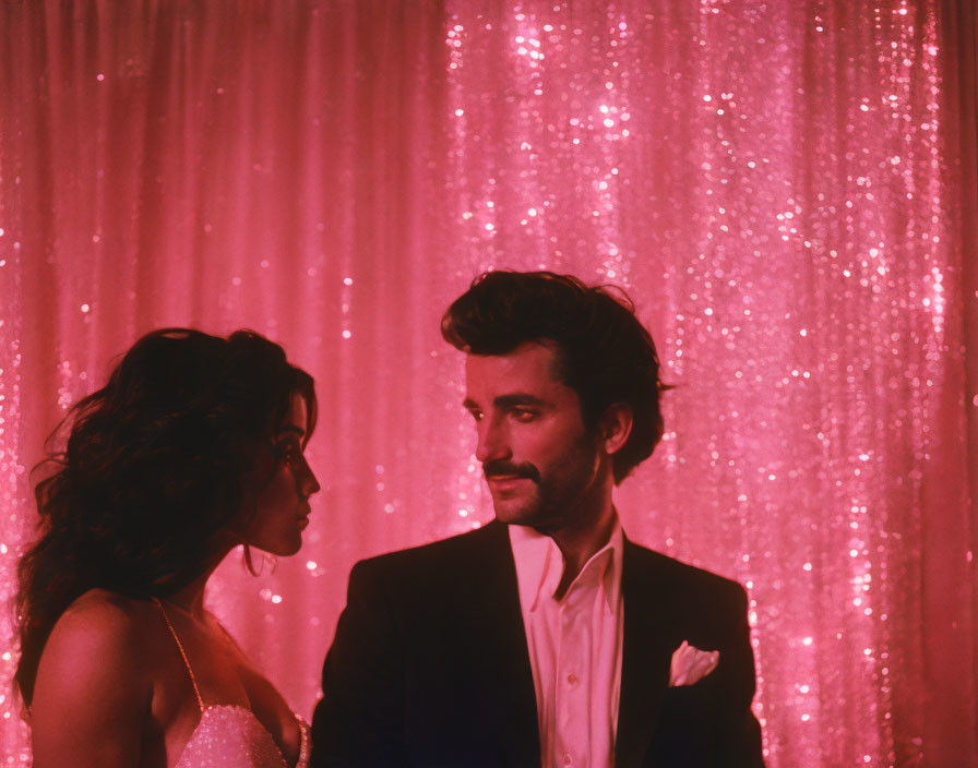 Man and woman in formal attire against pink sparkly background