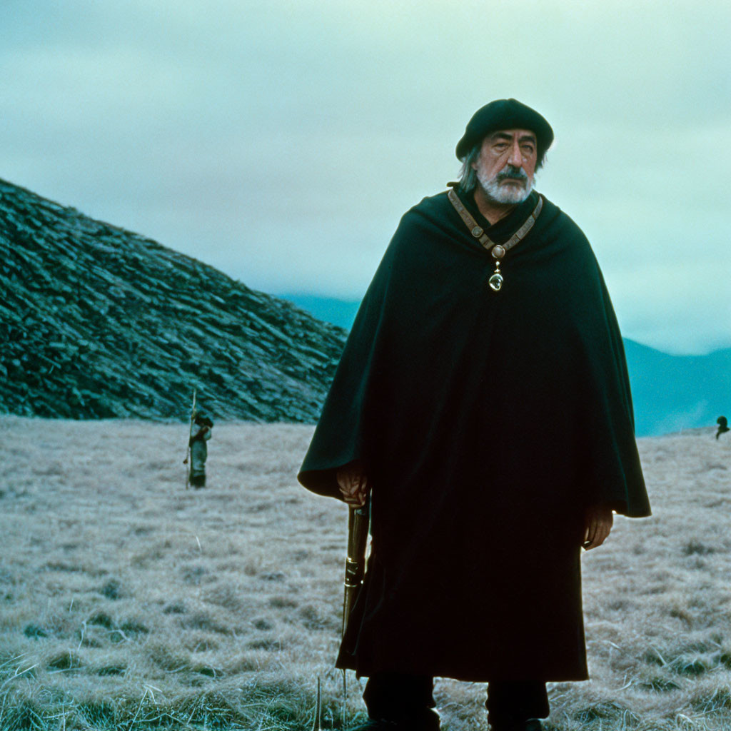 Bearded man with rifle on grassland, hills in background