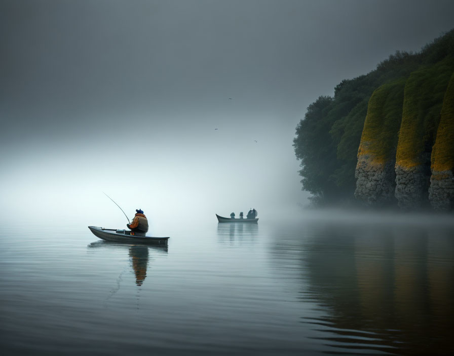 Two boats on calm, foggy water: one with a fisherman, the other with people near