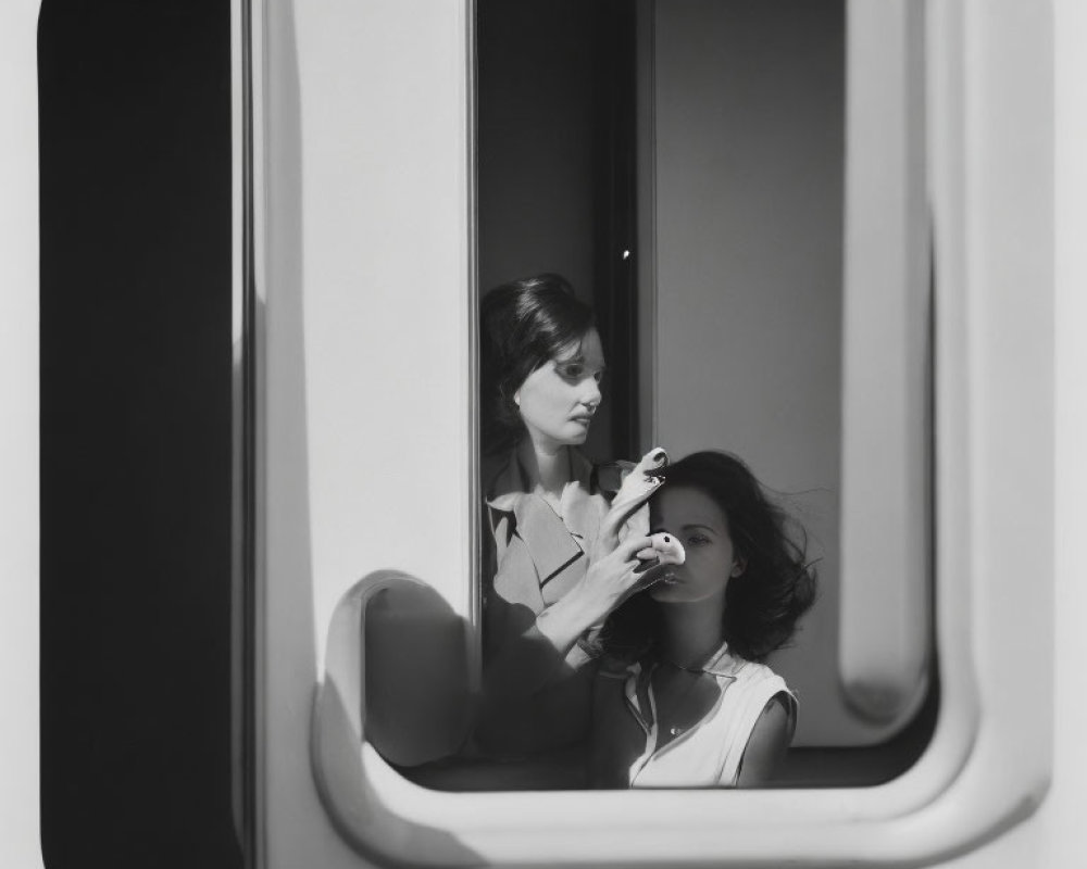 Woman applying lipstick in train window reflection.