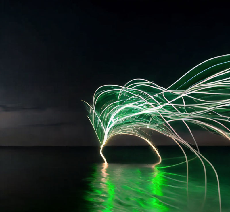 Nighttime light painting creates arched patterns on water.