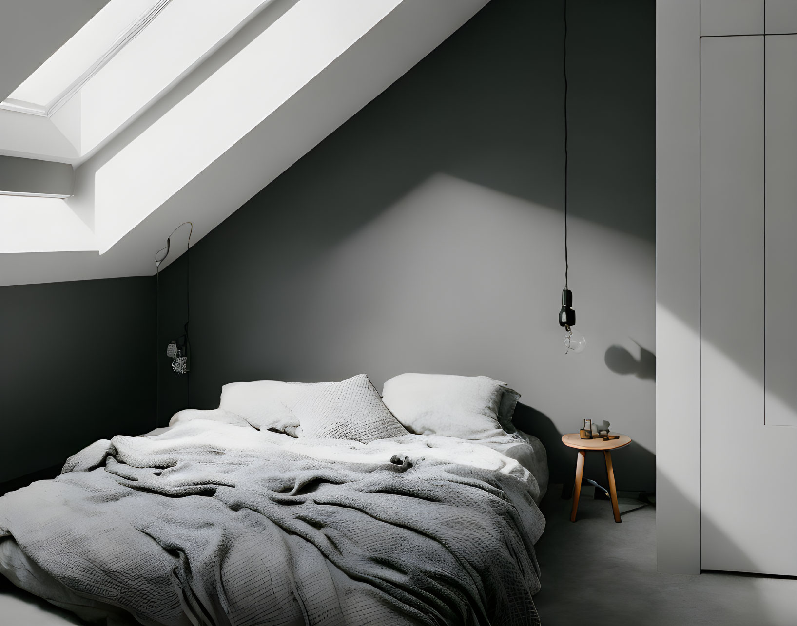 Unmade bed in minimalist bedroom with skylight and hanging bulbs