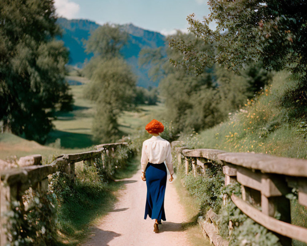 Person in Blue Skirt Walking on Rural Path with Wooden Fences and Green Fields