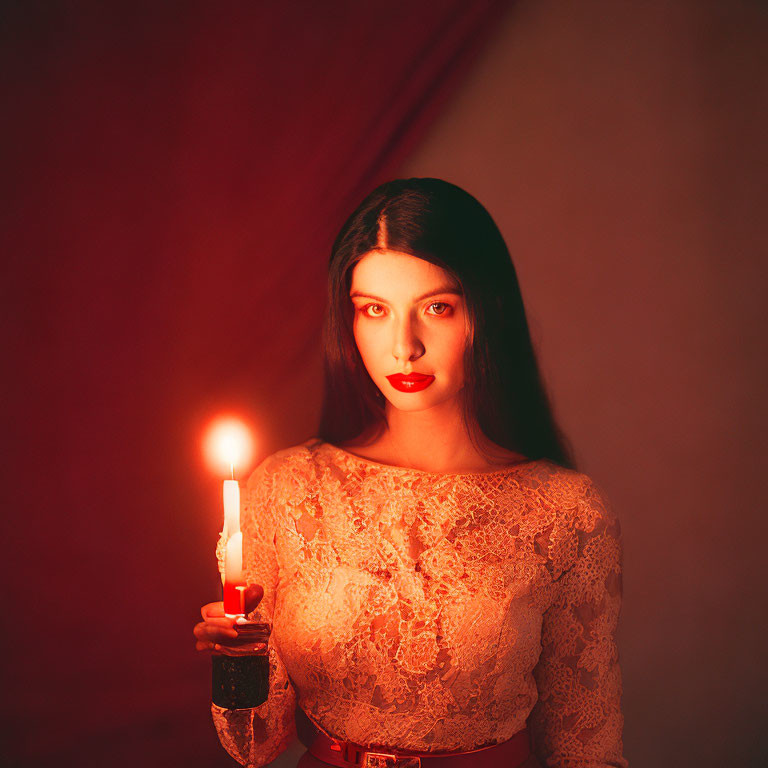 Woman in lace dress holding candle in dimly lit red room