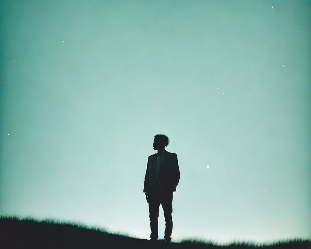 Silhouette of person on hilltop under starry night sky