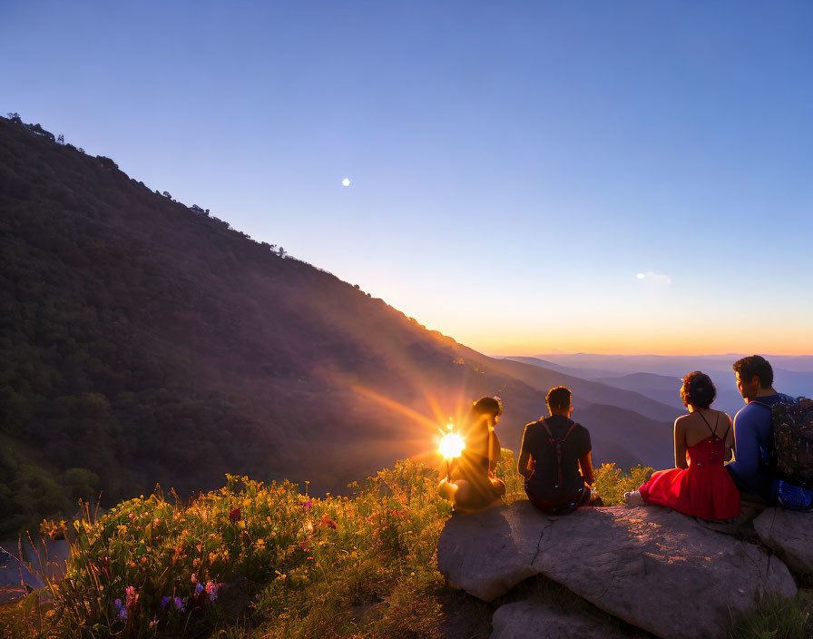 Sunset mountain ledge scene with four people overlooking valley.