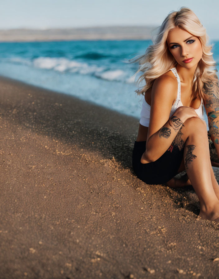 Blonde Woman with Tattoos on Sandy Beach by Ocean