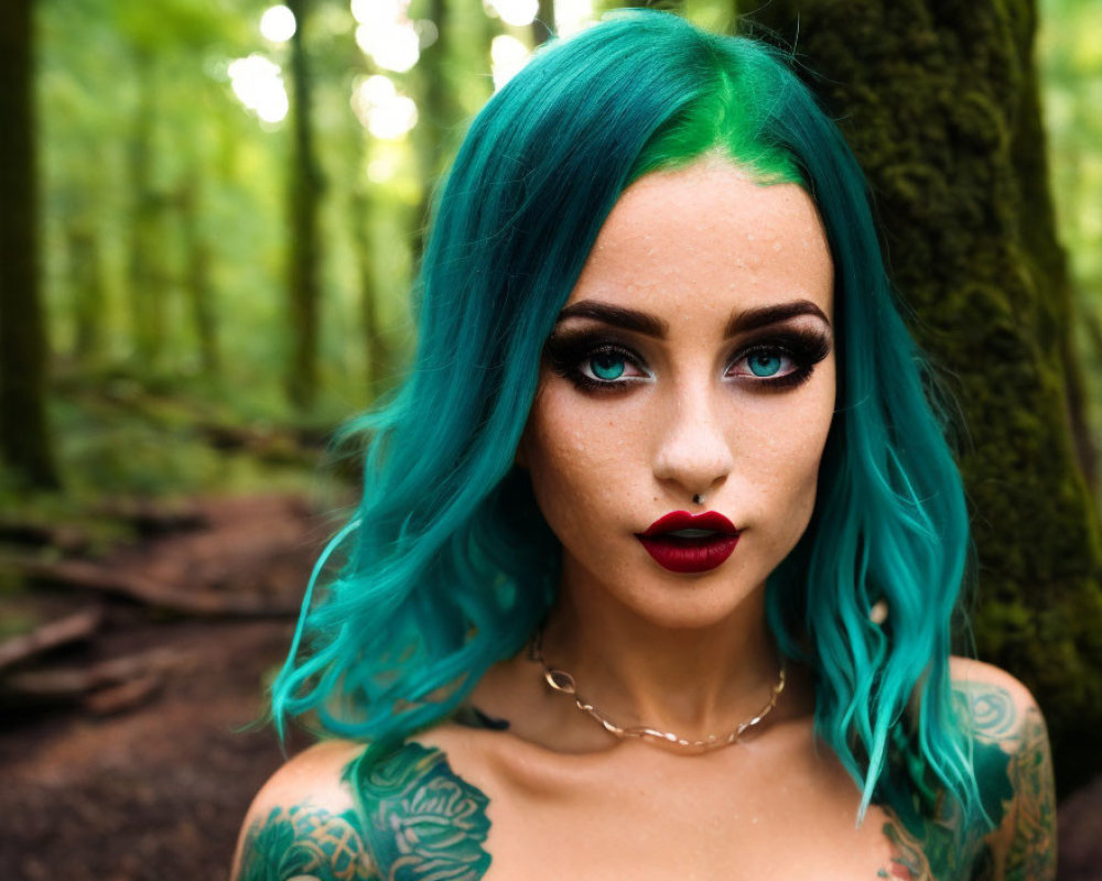 Vibrant teal-haired woman with red lipstick in forest, showcasing tattoos and confident gaze
