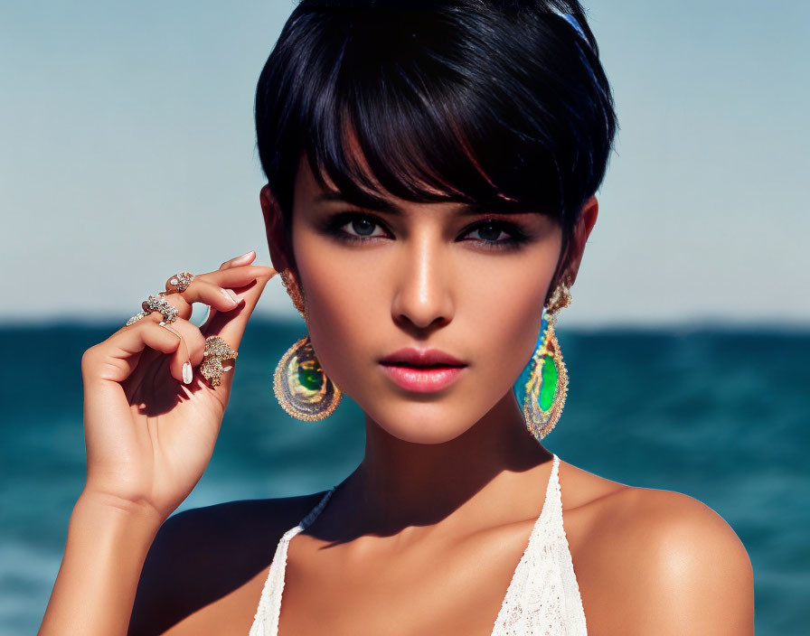 Short-haired woman in hoop earrings and white top by the sea