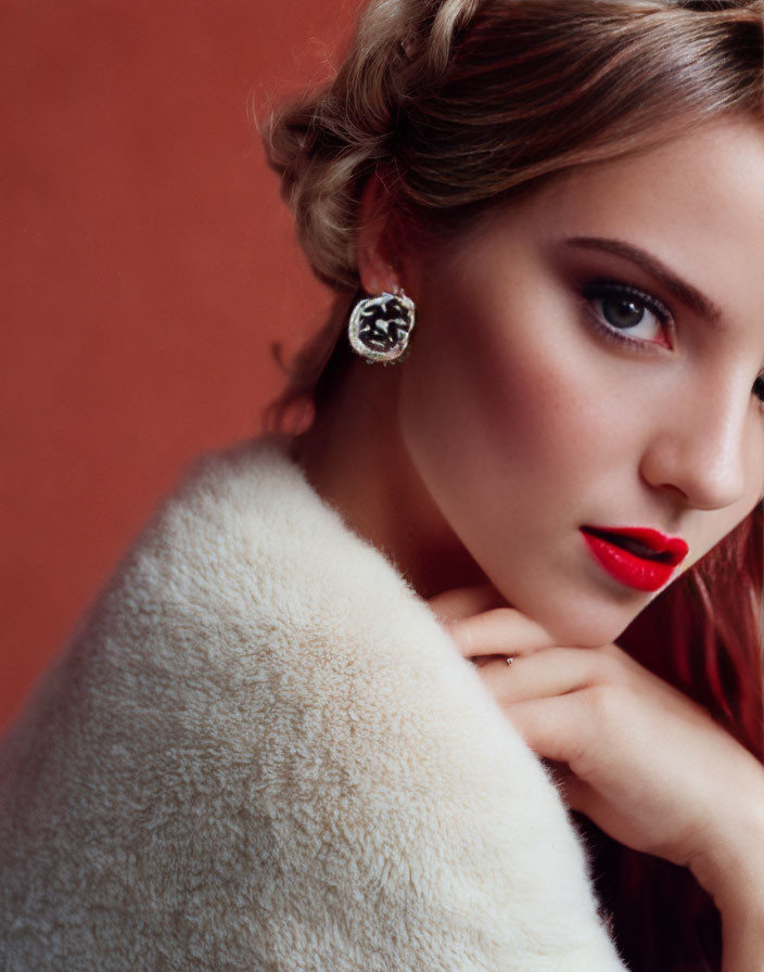 Woman with side-swept updo, red lipstick, dark eyeshadow, and white fur