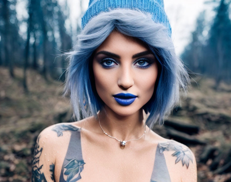 Blue-haired woman with tattoos in beanie against forest backdrop