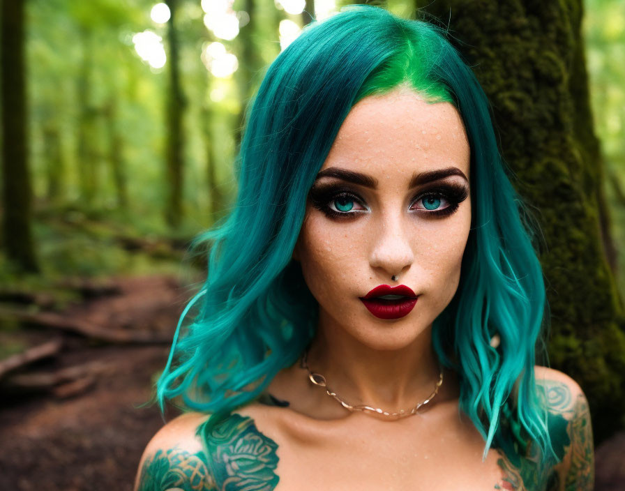 Vibrant teal-haired woman with red lipstick in forest, showcasing tattoos and confident gaze