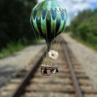 Crystal balloon with gem-like facets and golden trims above forest railway track