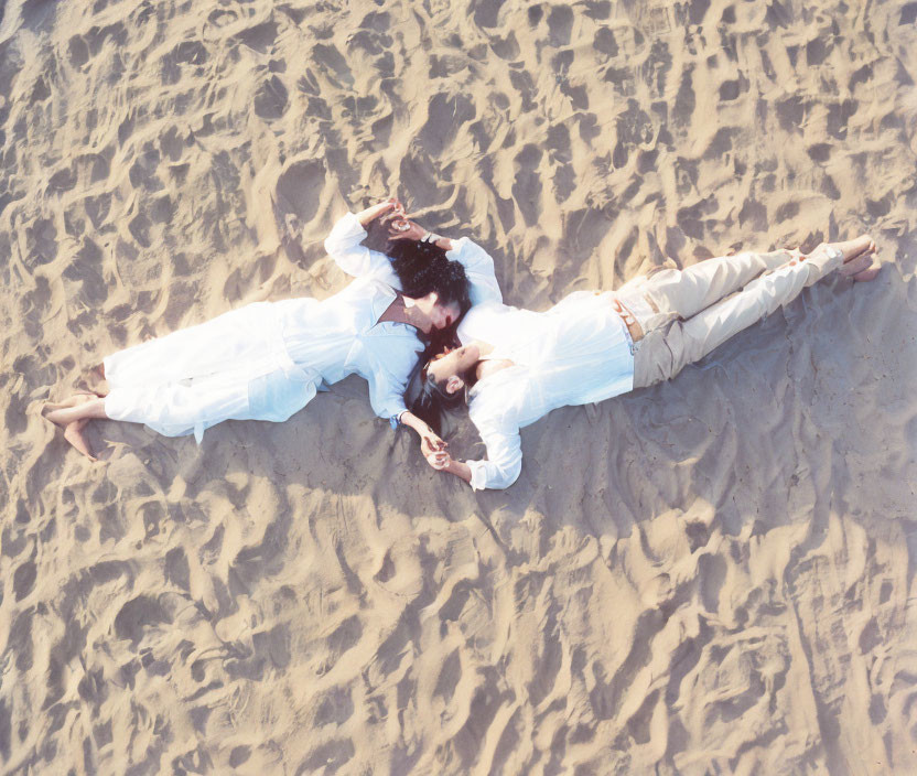 Mirrored image of two individuals lying in sand