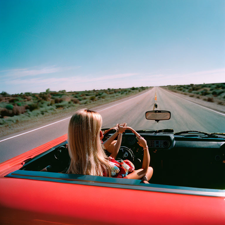 Blonde Woman Driving Red Convertible on Desert Road