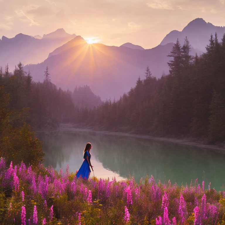 Woman in Blue Dress Standing by Lake with Purple Flowers and Sunlit Mountains