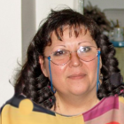 Portrait of woman with curly hair, glasses, blue earrings, in colorful collar top