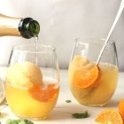 Sparkling Beverage Poured into Glass with Ice and Lemon, Citrus Slices on Table