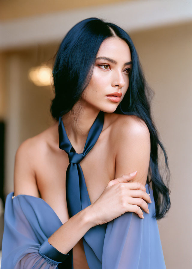 Elegant person with long blue hair in blue halter neck dress exudes sophistication