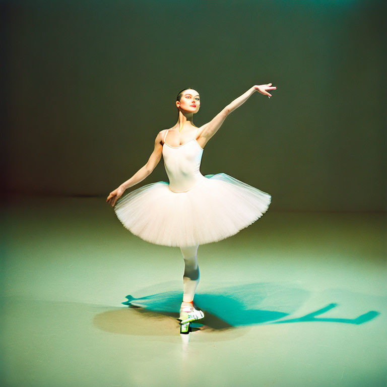Ballerina in white tutu performs on pointe with extended arm on brightly lit stage