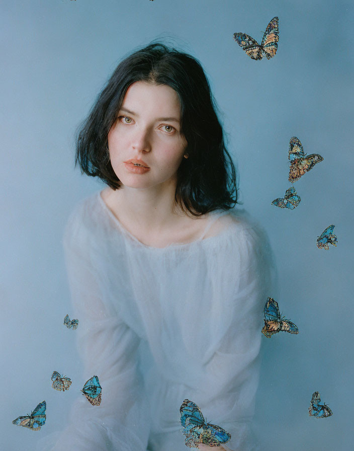 Dark-haired woman in white blouse surrounded by butterflies on blue background