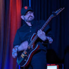 Stylish individual plays futuristic guitar in blue-lit room
