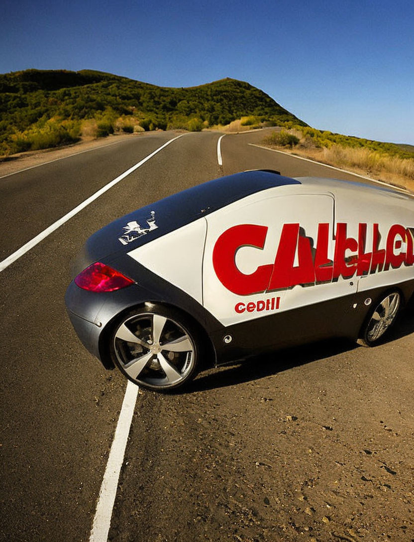 Branded car with custom advertising graphics on empty road in hilly terrain
