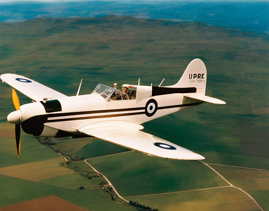 Vintage Single-Propeller Aircraft Flying Over Green Fields
