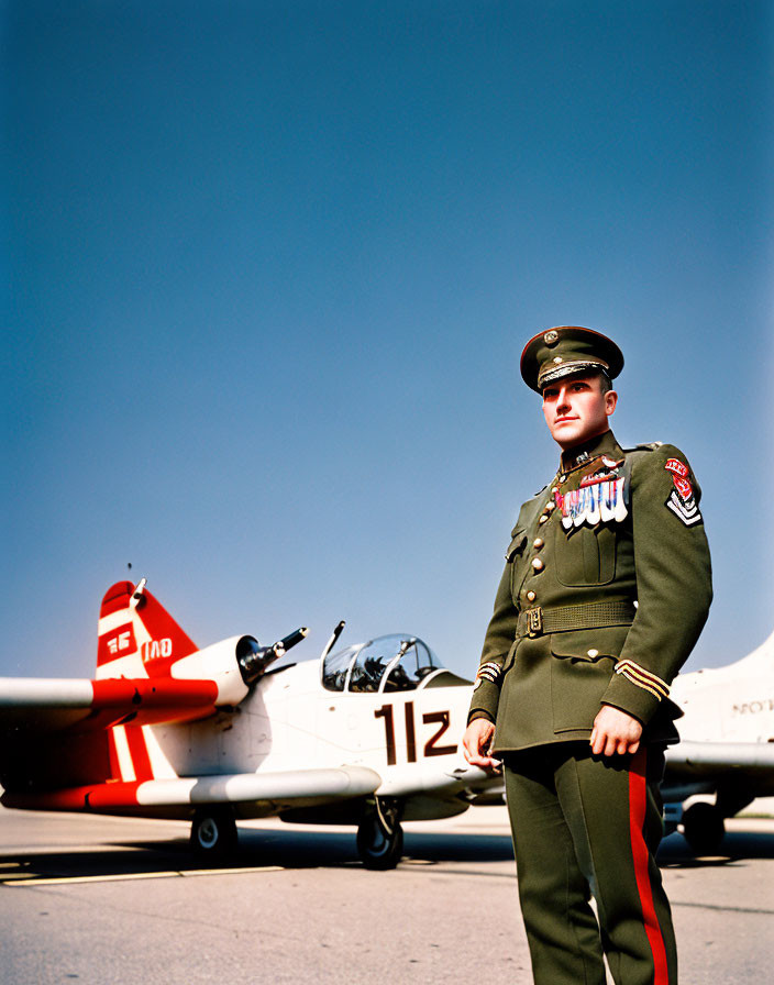 Military officer with medals in front of propeller aircraft under clear blue sky