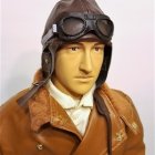 Vintage pilot in uniform with medals, leather helmet, goggles, and fur collar.