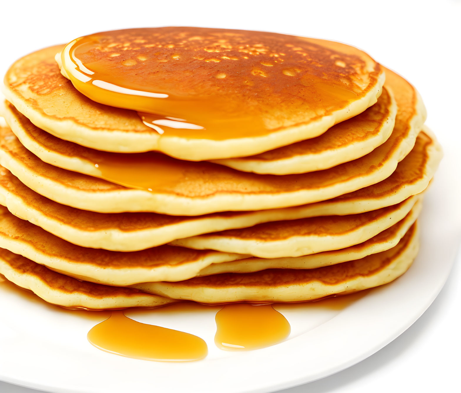 Golden pancakes with syrup on white plate