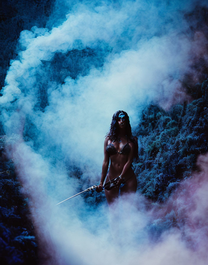 Person in Dark Attire with Sword in Mystic Blue Smoke Amid Shadowy Forest