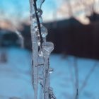 Icicle with dripping water, sunlight bokeh effect, winter landscape