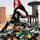 Stylized woman on chair surrounded by colorful garbage and old buildings